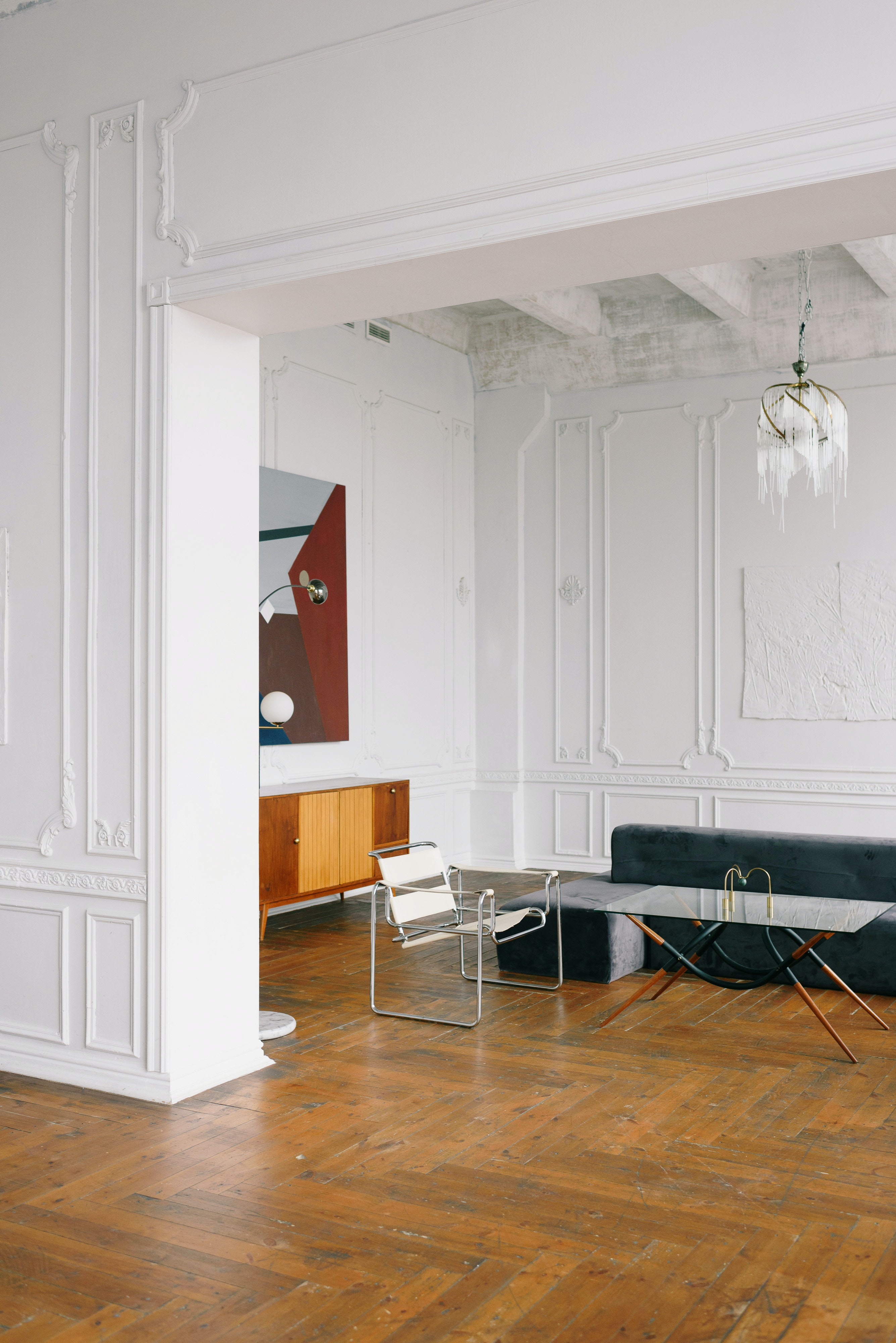 Minimalist office interior with modern art, glass table, and wooden flooring